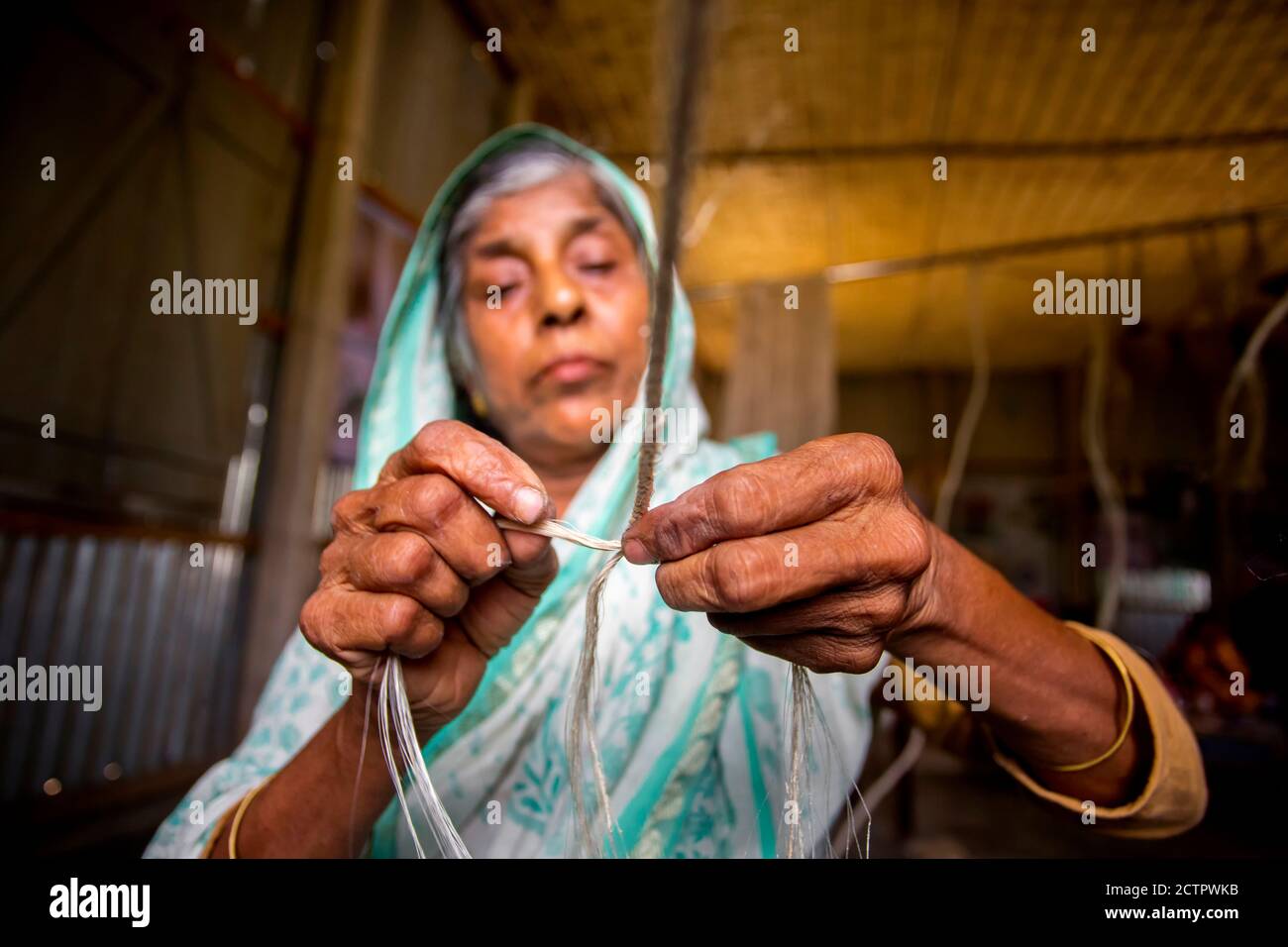 An old age woman is making on his skinny hands a rope from the banana