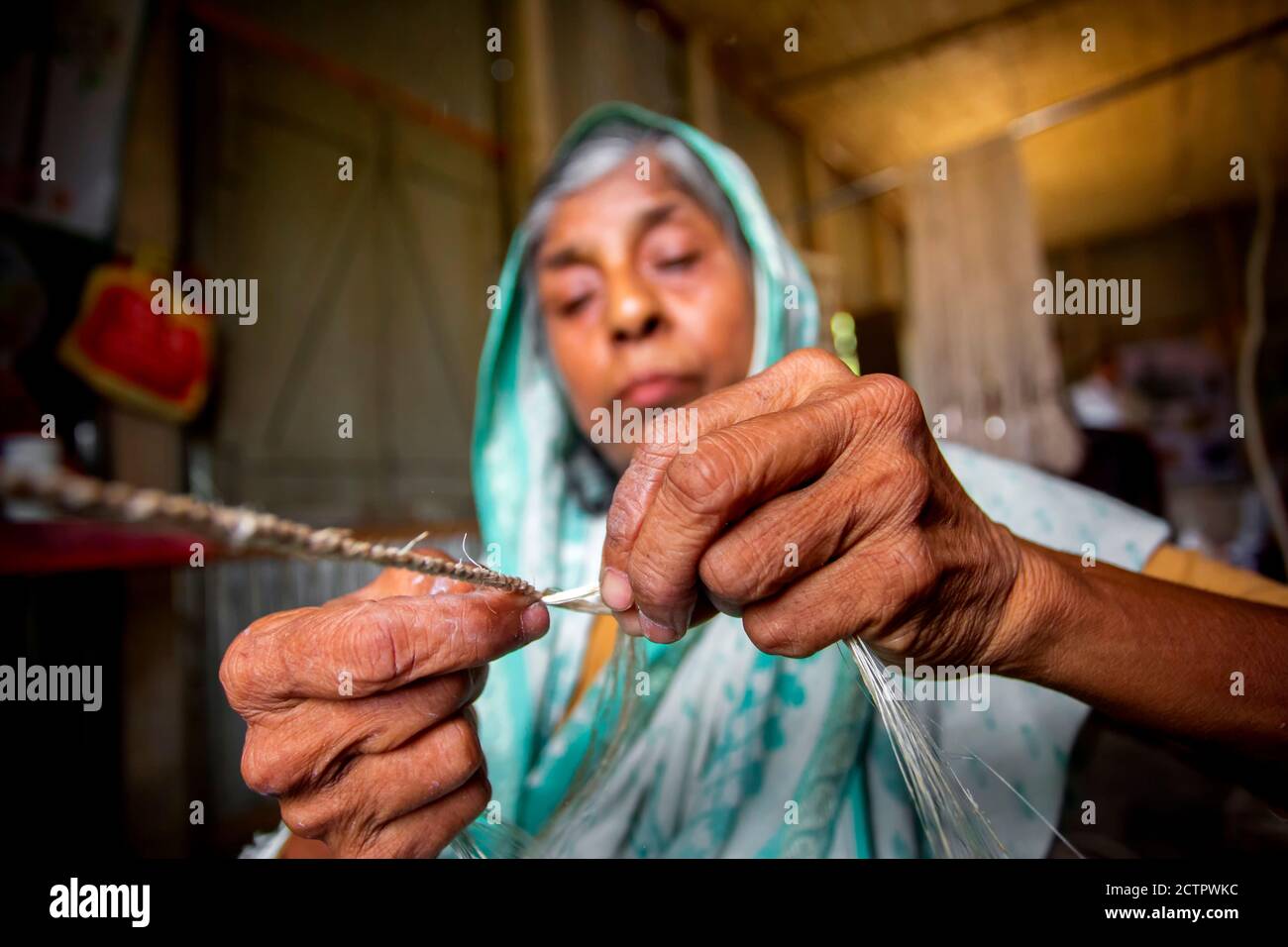 An old age woman is making on his skinny hands a rope from the banana