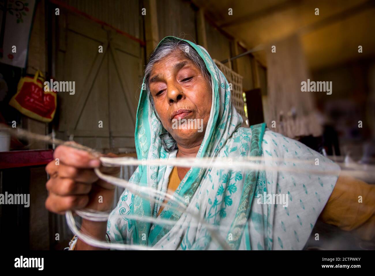 An old age woman is making on his skinny hands a rope from the banana