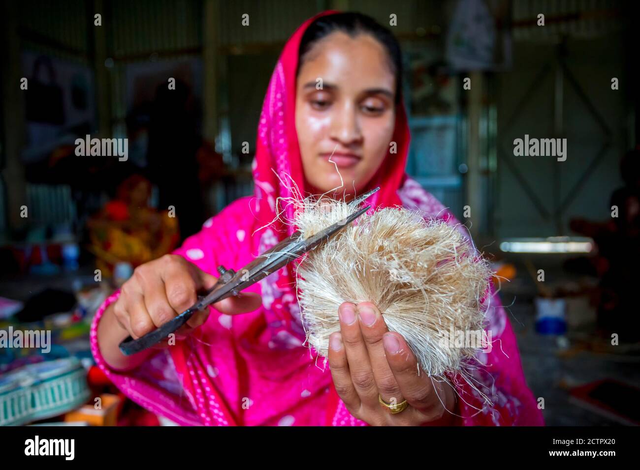 A woman making handicrafts is smoothing the fibers of a banana tree