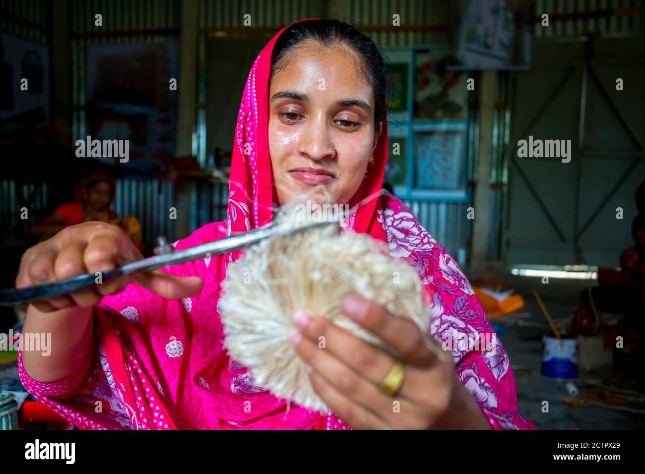 A woman making handicrafts is smoothing the fibers of a banana tree