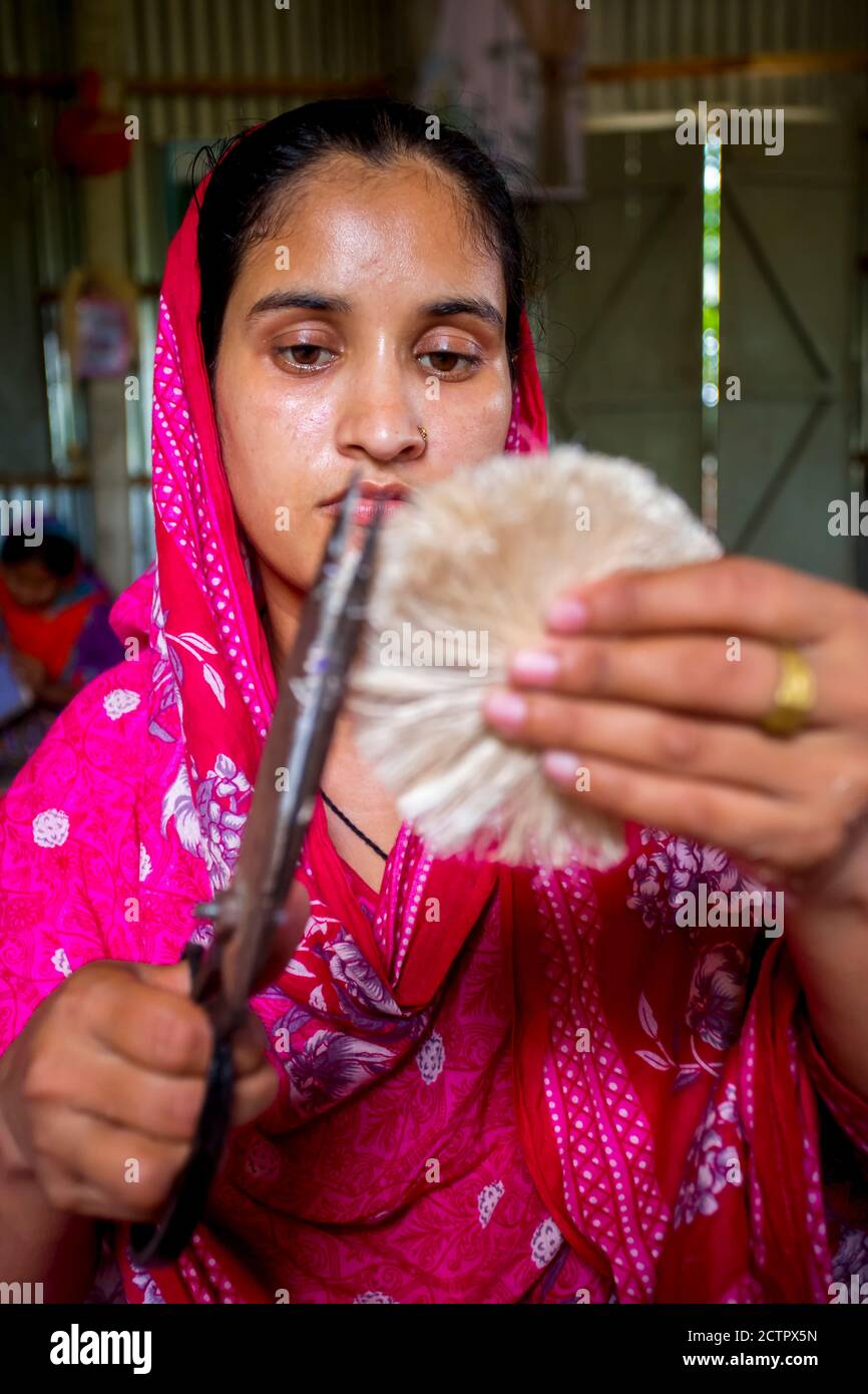 A woman making handicrafts is smoothing the fibers of a banana tree