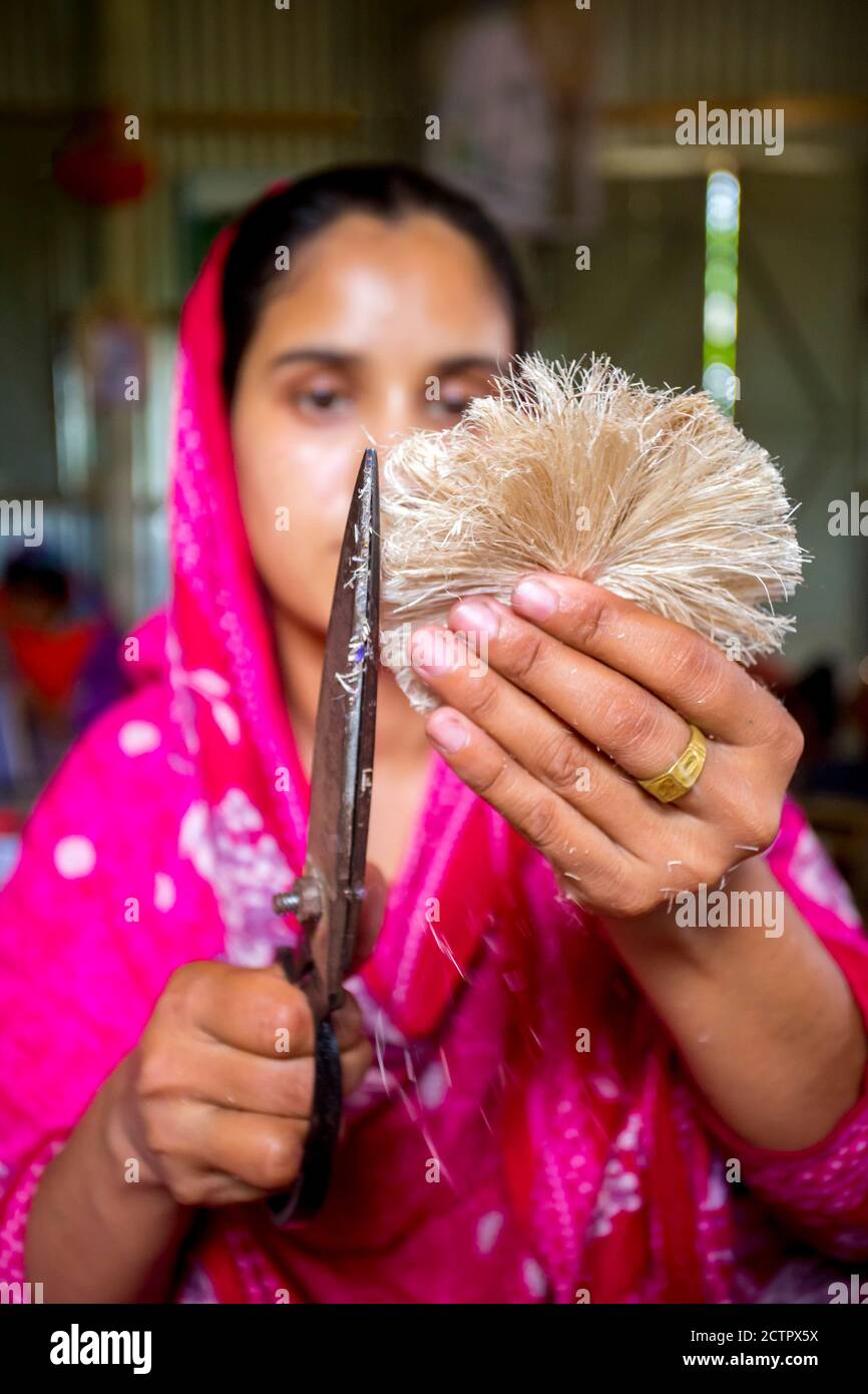 A woman making handicrafts is smoothing the fibers of a banana tree