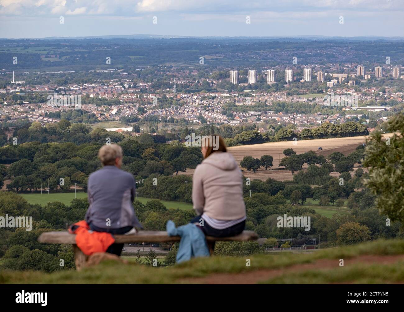 Walkers rest on a bench on top of the Clent Hills, Worcestershire overlooking part of the Black Country area. Stock Photo