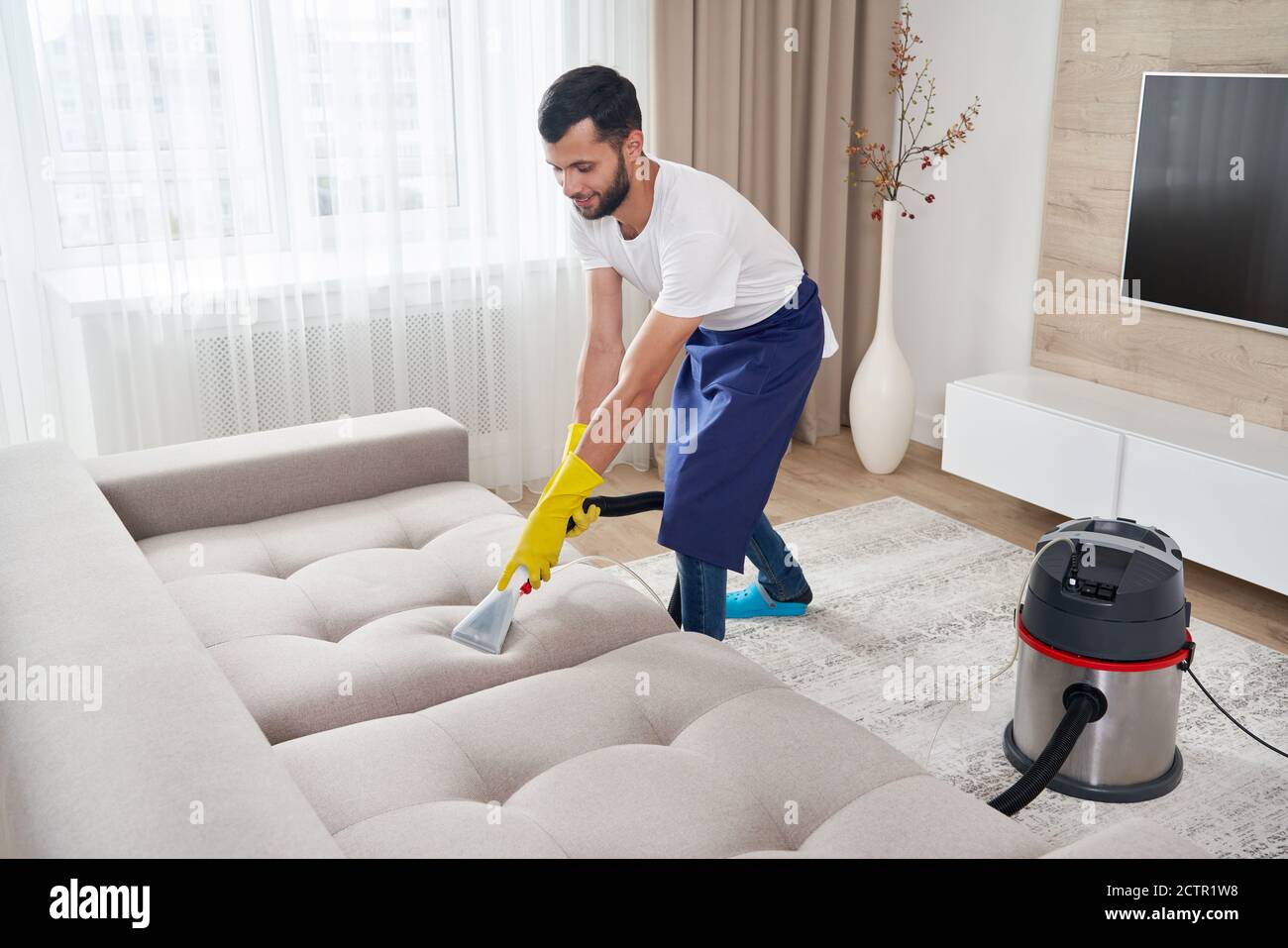 Close-up of housekeeper holding modern washing vacuum cleaner and