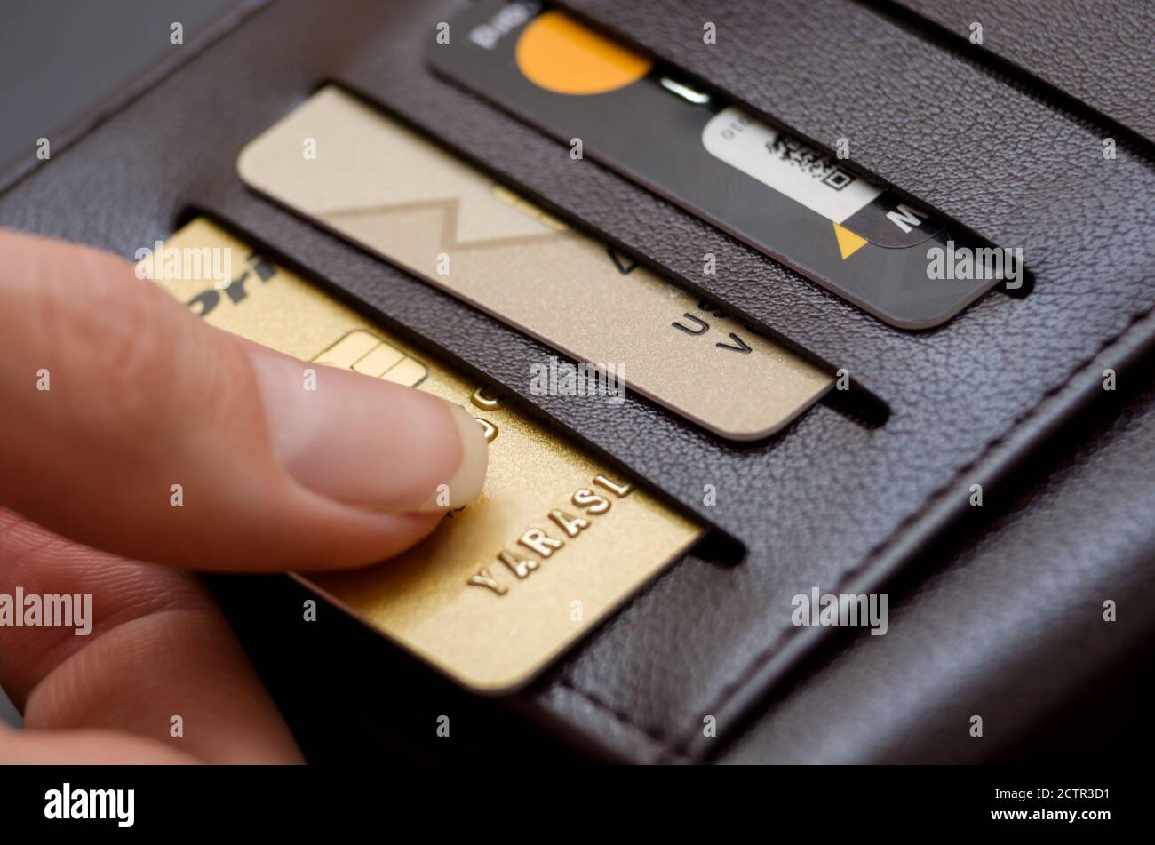 Women's hand pulls out a credit card from a black purse Stock Photo