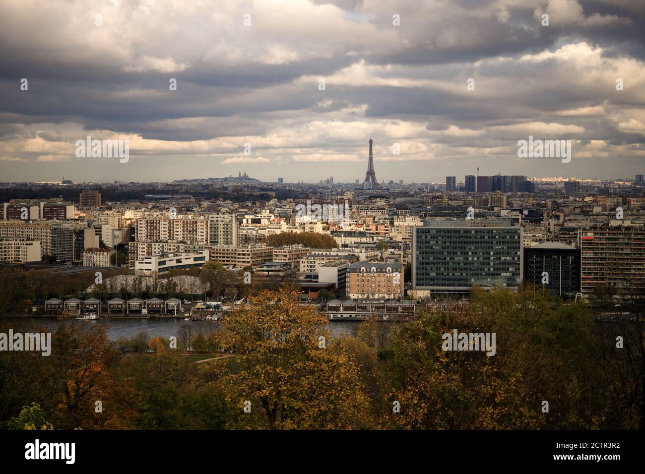 View of Paris city with Eiffel Tower and Mont Martre. Dramatic sky in fall. Sene river. Stock Photo