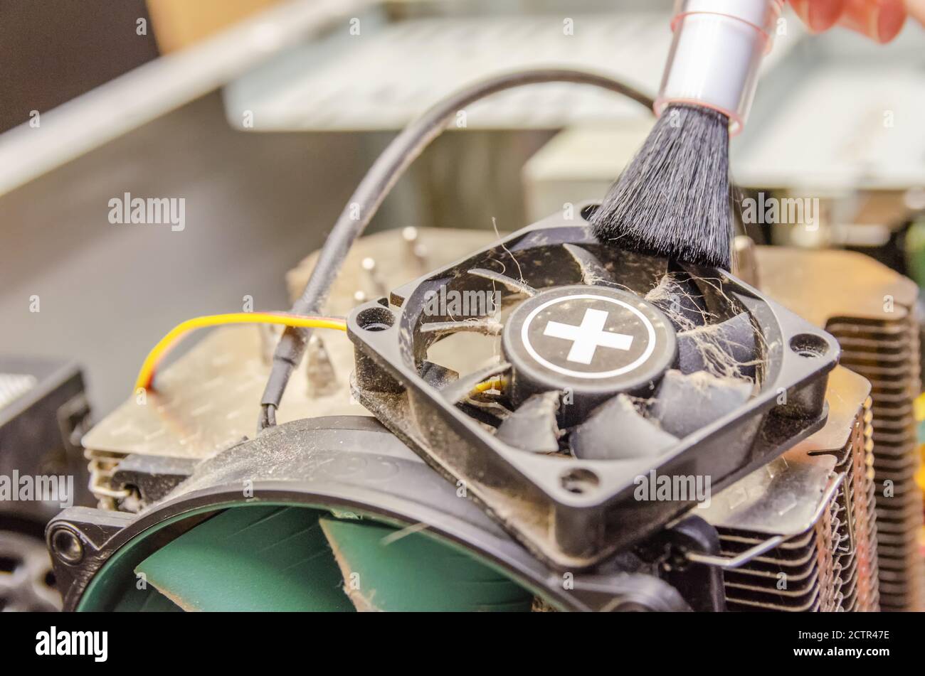 Dust on computer PC CPU cooler. Cleaning the computer cooler with a red brush. concept of maintenance of the main components of the computer Stock Photo