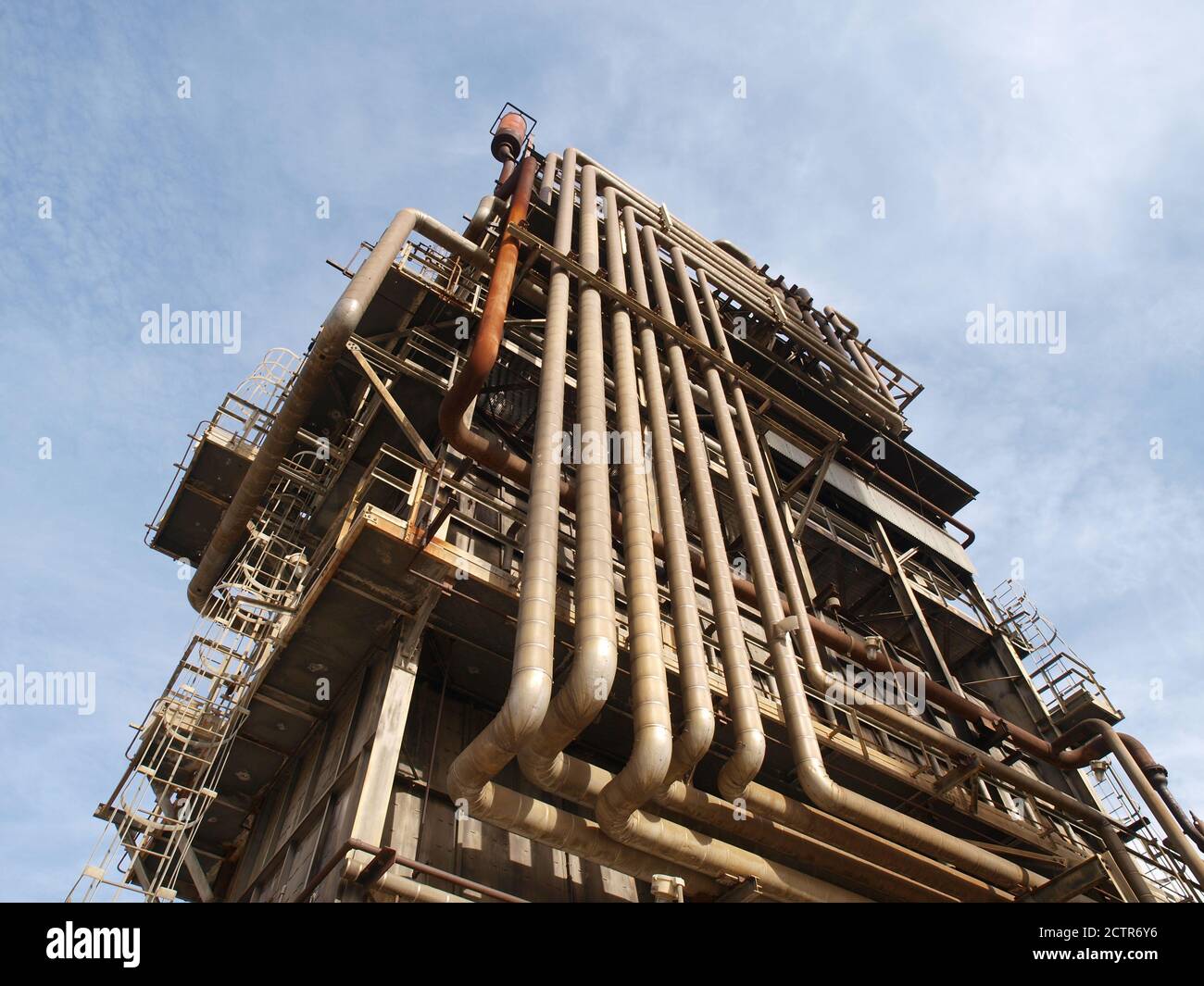 View of old rusty industrial pipe covered oil and petrochemical refinery tower. Stock Photo