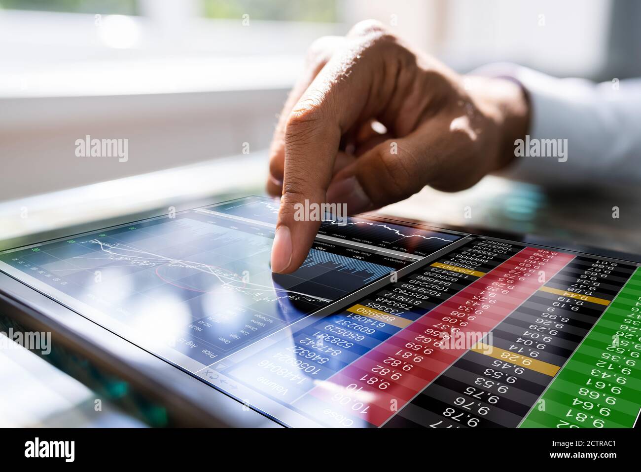 African Man Using Stock Market Data On Tablet Stock Photo