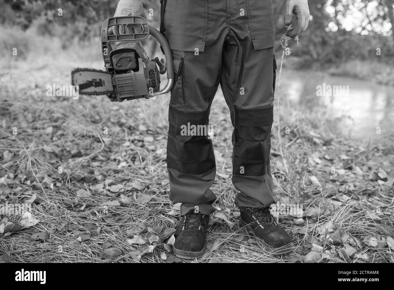 Grayscale shot of a lumberjack with a chainsaw in a forest Stock Photo