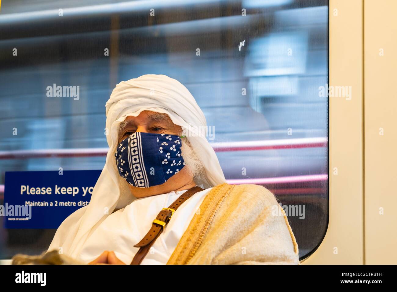 LONDON, ENGLAND - JULY 6, 2020: Elderly white haired man wearing an Arabic Keffiyeh headscarf and a face mask on the London Underground during the COV Stock Photo