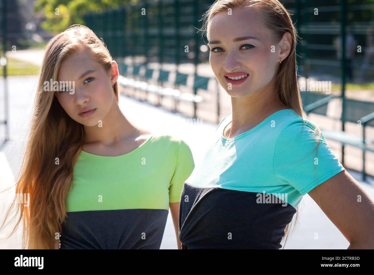 Sportive woman and girl models in sportswear on the sports ground at sunny day. Portrait Stock Photo
