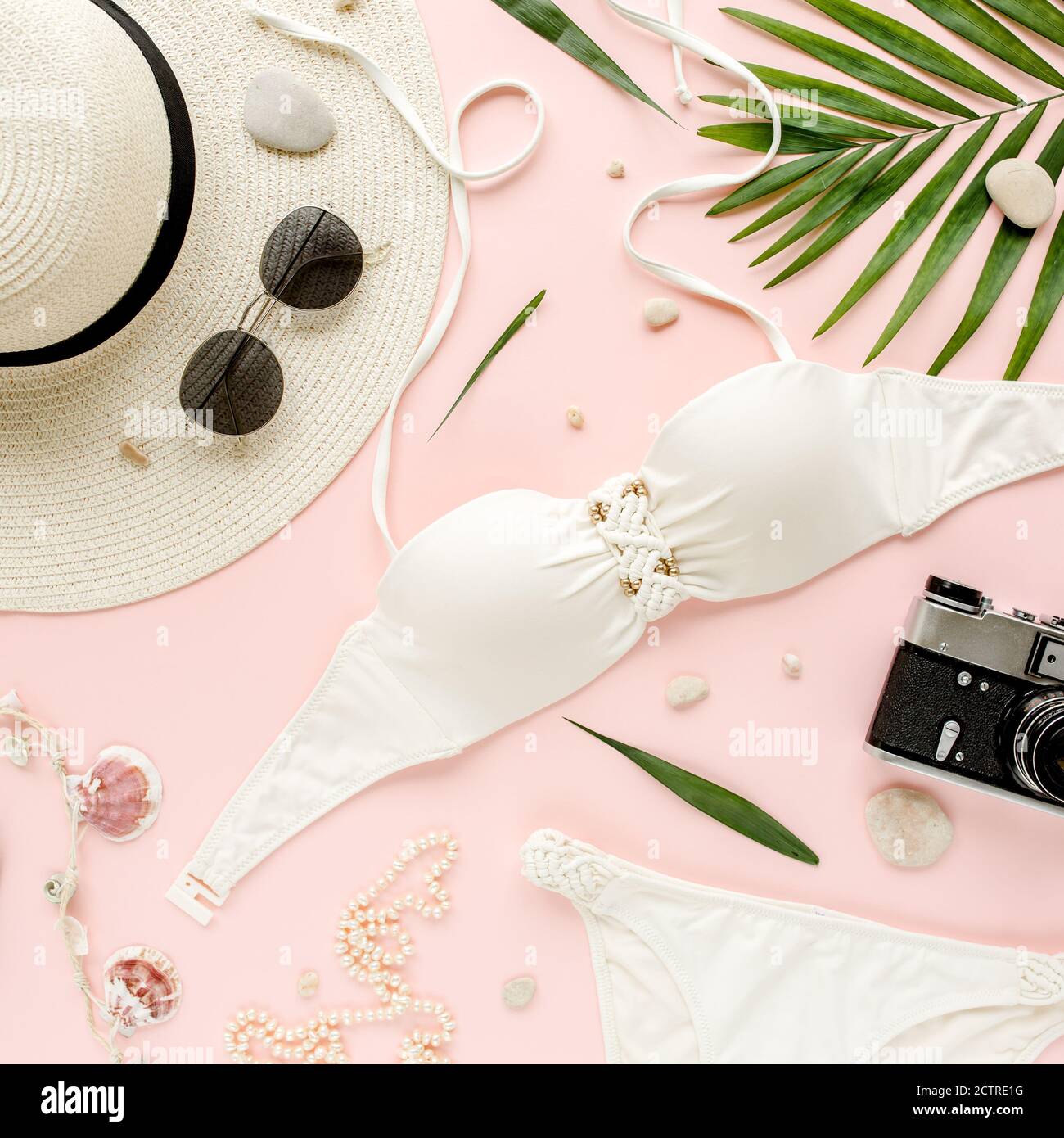 Traveler accessories, women summer bikini set swimsuit, tropical palm leaf branches on pink background. Travel vacation concept. Flat lay, top view.  Stock Photo