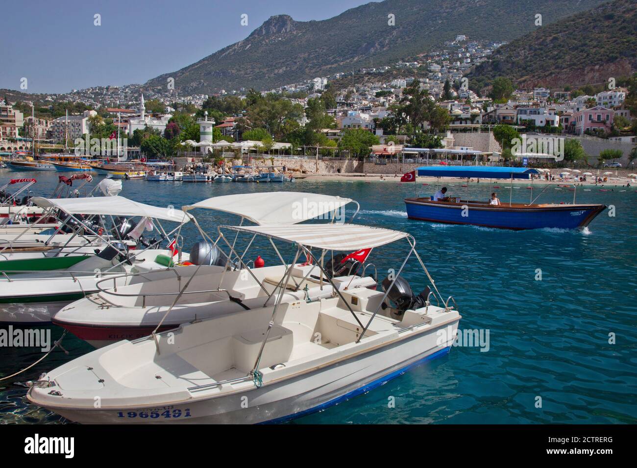 A water taxi passes small motorboats as it leaves the harbour  of Kalkan in Turkey.  Kalkan is a popular holiday destination and is located on the Tur Stock Photo