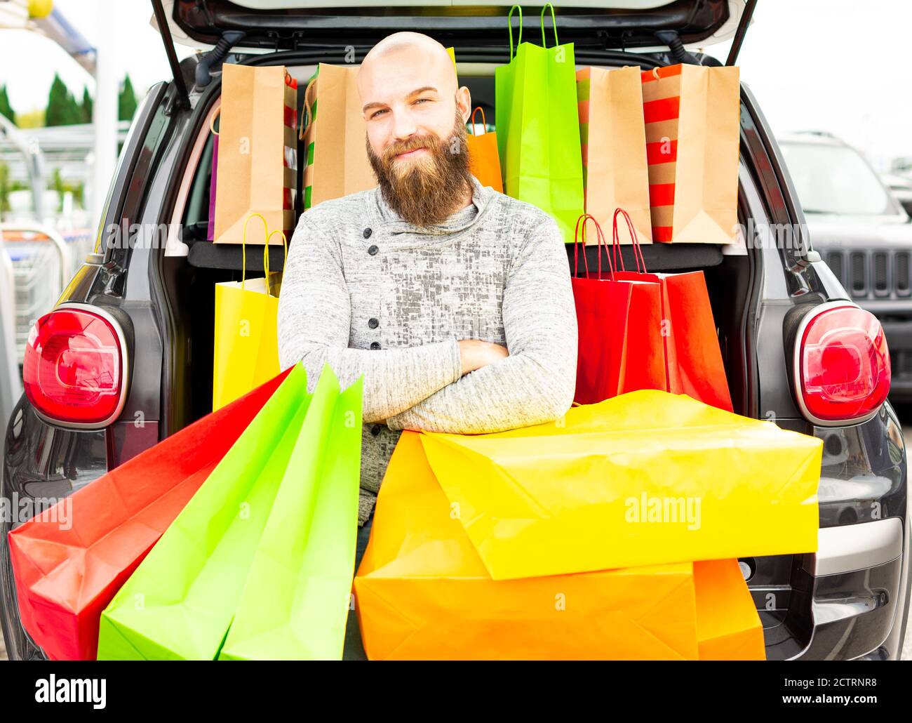Smiling man having fun with lots of bags on a shopping day for the black friday. Concept about how fun is to buy things on these promotional days. Stock Photo