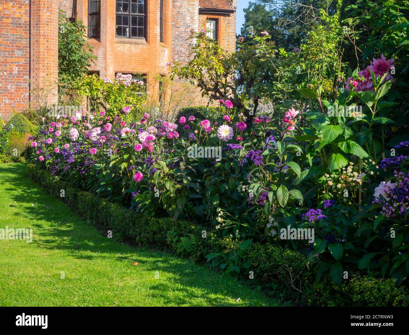 Chenies Manor House and Garden on a sunny September afternoon, 2020. Colourful dahlias, herbaceous plant borders, lawn. Stock Photo