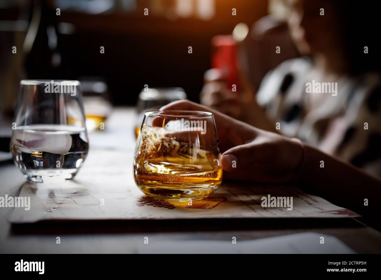 Glass with alcohol in hand. Stock Photo