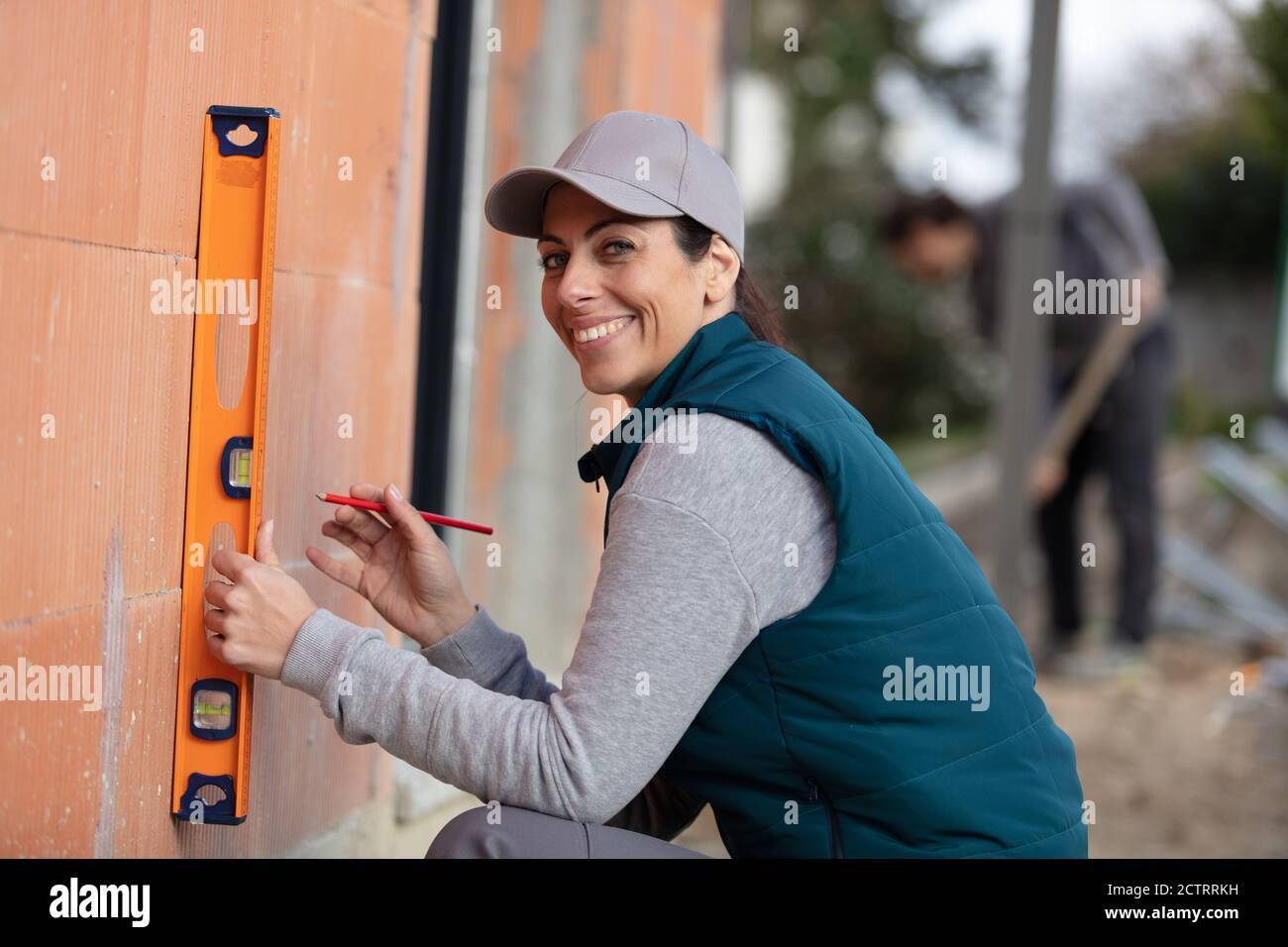 attractive young female construction worker checking level of the wall Stock Photo