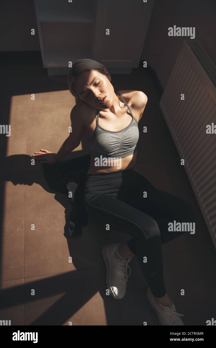 Upper view photo of a blonde woman in sportswear relaxing on the floor after fitness exercises at home Stock Photo
