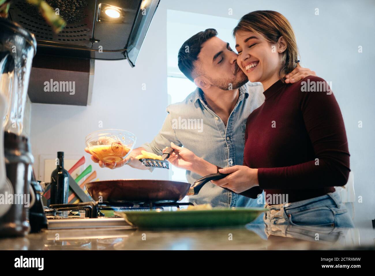 Husband And Wife Cooking Together Hugging And Kissing Stock Photo