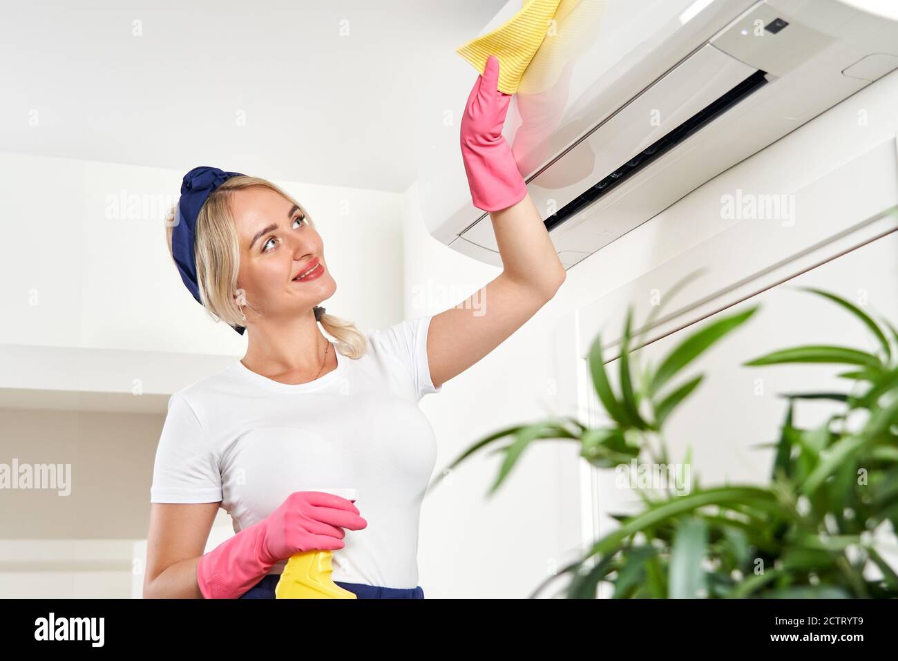 Woman cleaning air conditioner with rag. Cleaning service or housewife concept Stock Photo