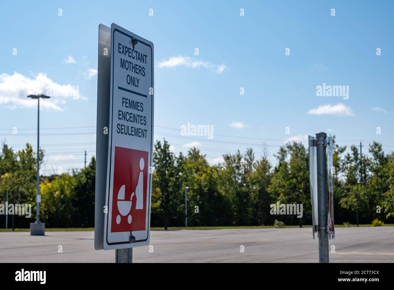 A bilingual sign in an Ottawa, Ontario parking lot marks a parking space as reserved for expectant mothers only in both English and French languages. Stock Photo
