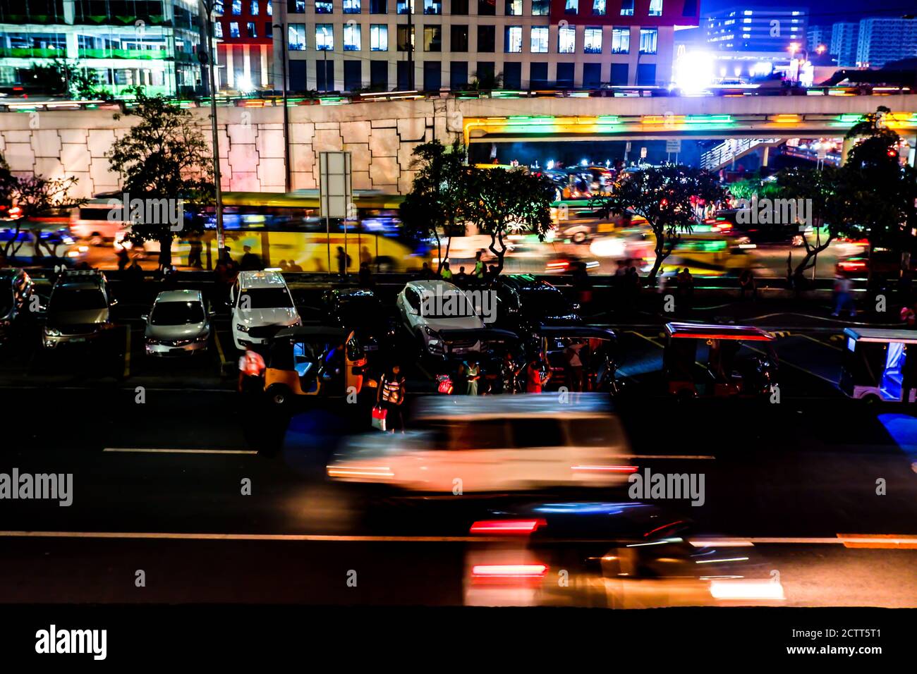 Bright city night lights and blurry transportation and pedestrians during rush hour Stock Photo