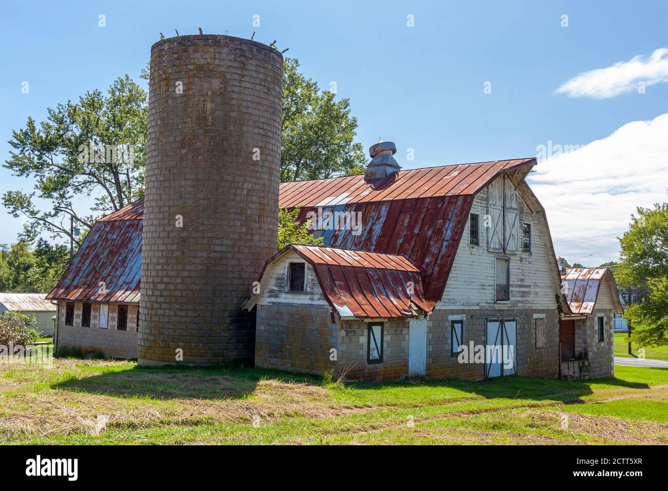 An abandoned old farm house with a tall brick silo and a big barn with ...