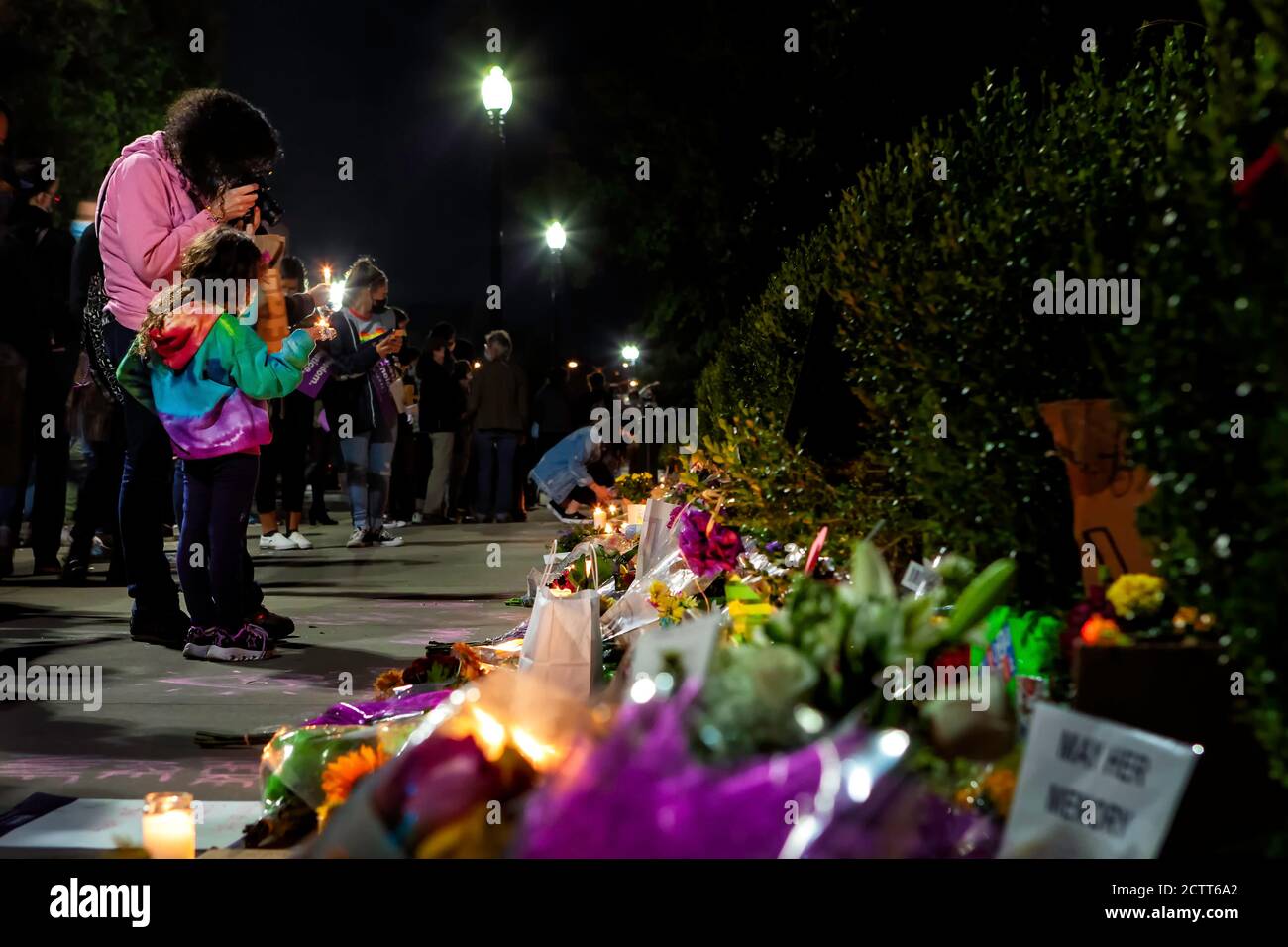 Mother and daughter holding a candle in front of the flowers and candles in honor of Justice Ruth Bader Ginsburg, Washington, DC, United States Stock Photo