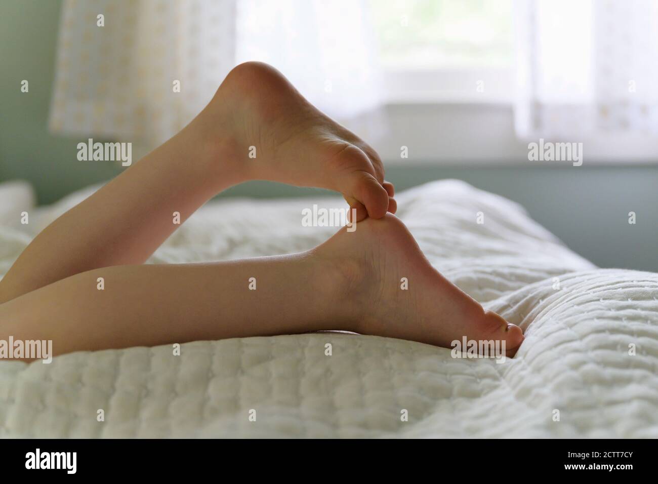 Low section of child (4-5) lying on bed Stock Photo