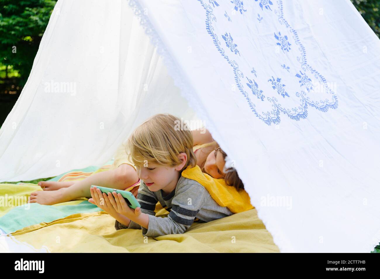 Girl (6-7) and boy (4-5) relaxing in homemade tent in backyard Stock Photo  - Alamy