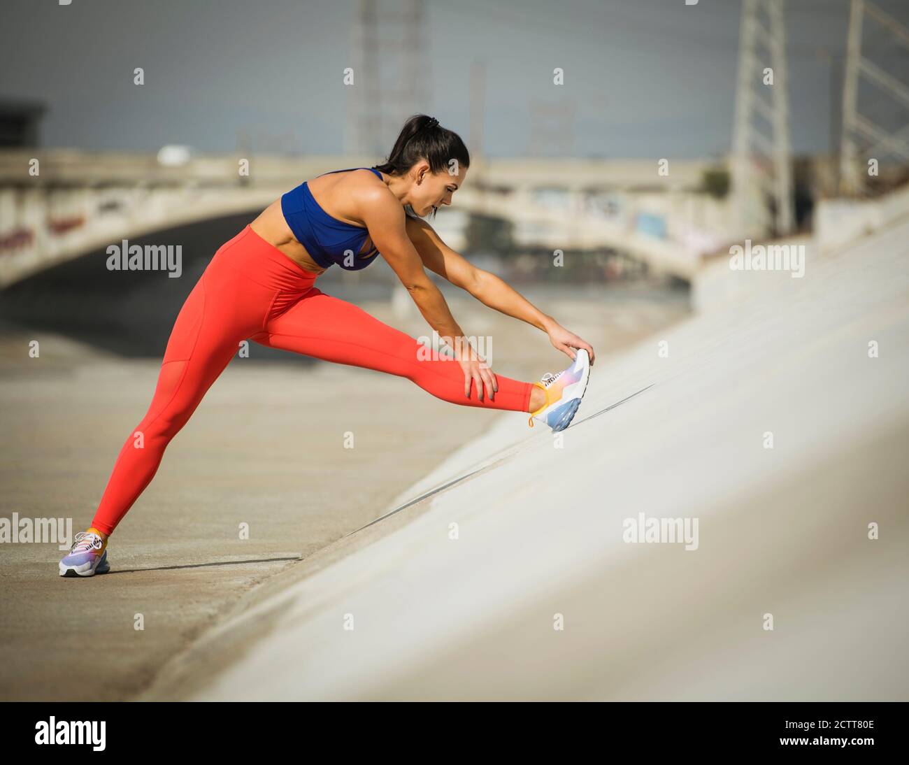 USA, California, Los Angeles, Sporty woman stretching in urban setting Stock Photo