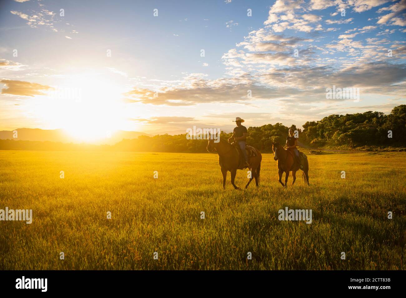 USA, Utah, Salem, Father and daughter (14-15) riding horses at sunset Stock Photo