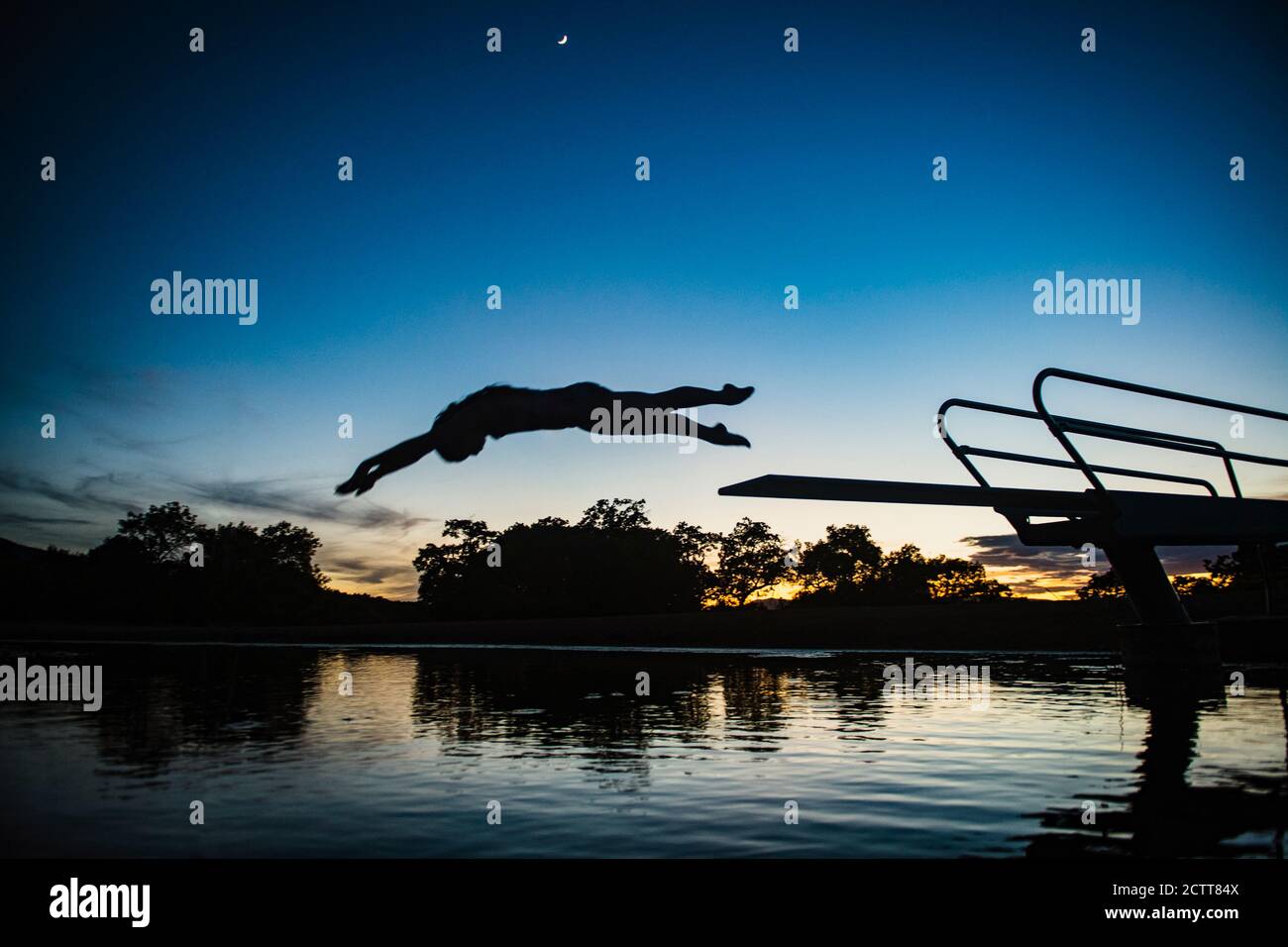 USA, Utah, Salem, Teenage girl (14-15) jumping from pier into lake at dusk Stock Photo