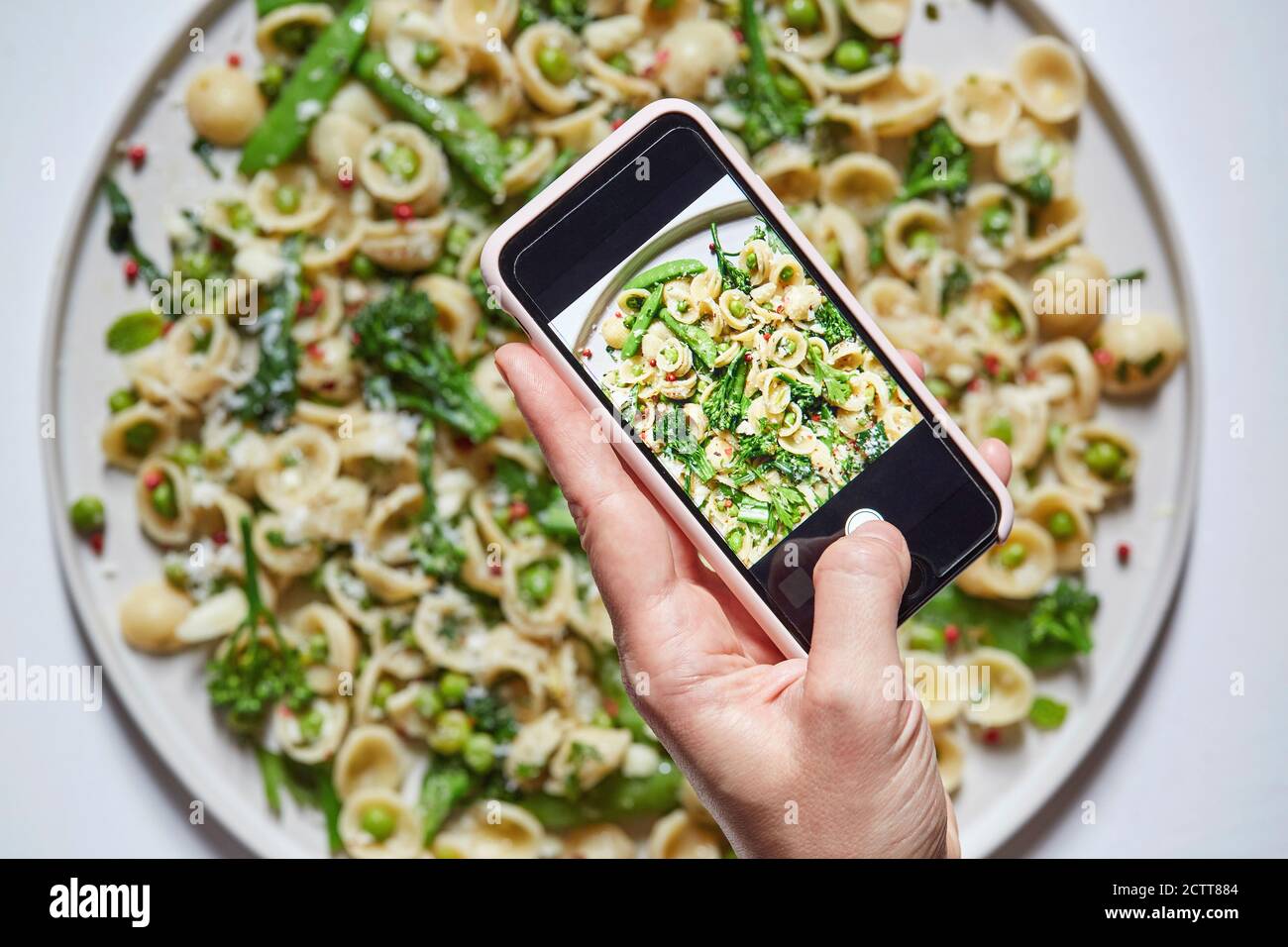 Woman's hand photographing orecchiette with smartphone Stock Photo