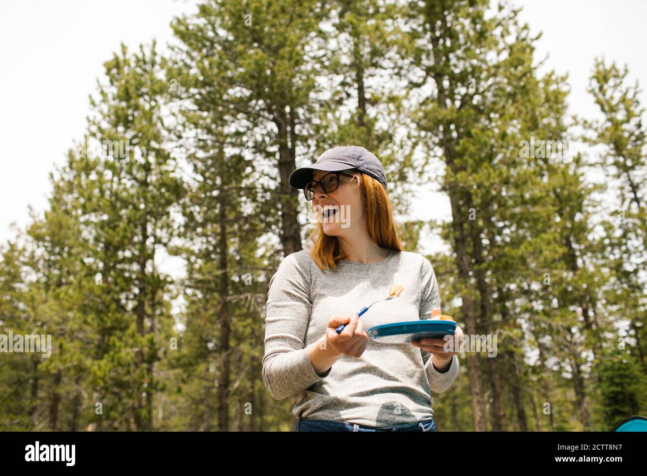 Smiling woman holding plate on camping in forest, Wasatch-Cache National Forest Stock Photo
