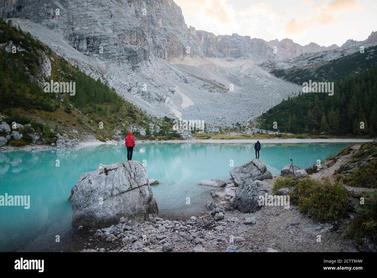 Italy, South Tyrol, Cortina d Ampezzo, lake Sorapis, Men standing on top of rock formations looking at view Stock Photo