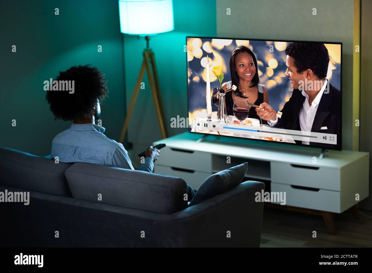 African Man Watching TV Movie Or Television Stock Photo