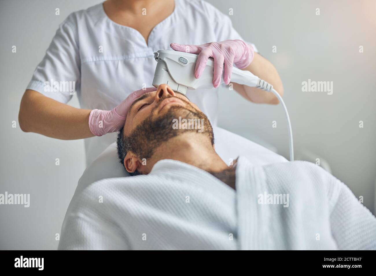 Female beautician treating male skin with laser device Stock Photo