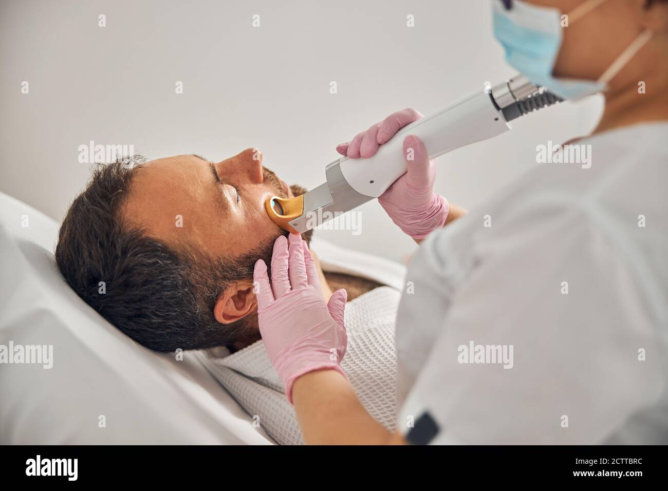 Esthetician in sterile gloves performing laser hair removal procedure