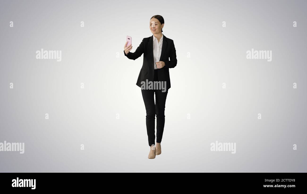 Young female in a suit having business video call on her phone o Stock Photo