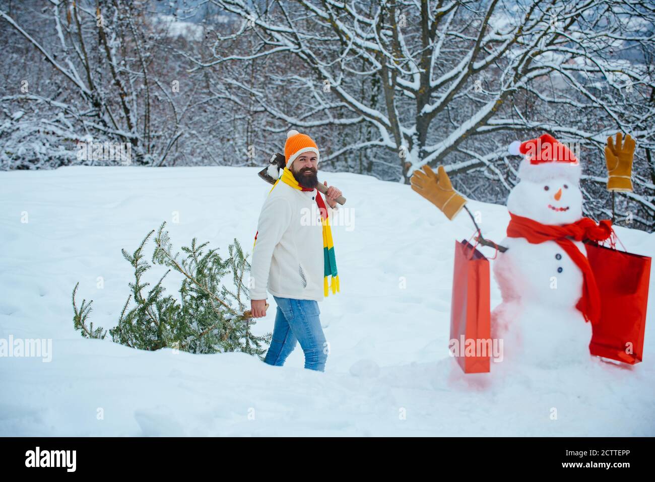 Young lumberjack bears fir tree in the white snow background. A