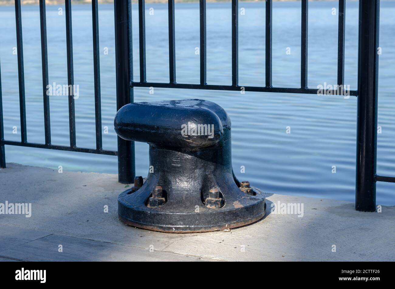 Empty mooring bollard at the dock. Black massive mooring hook for