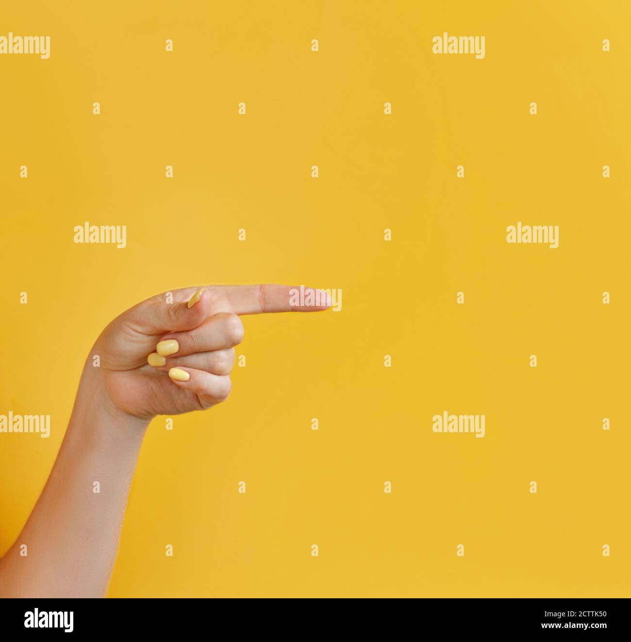 Close up of female hand pointing away on yellow background Stock Photo ...