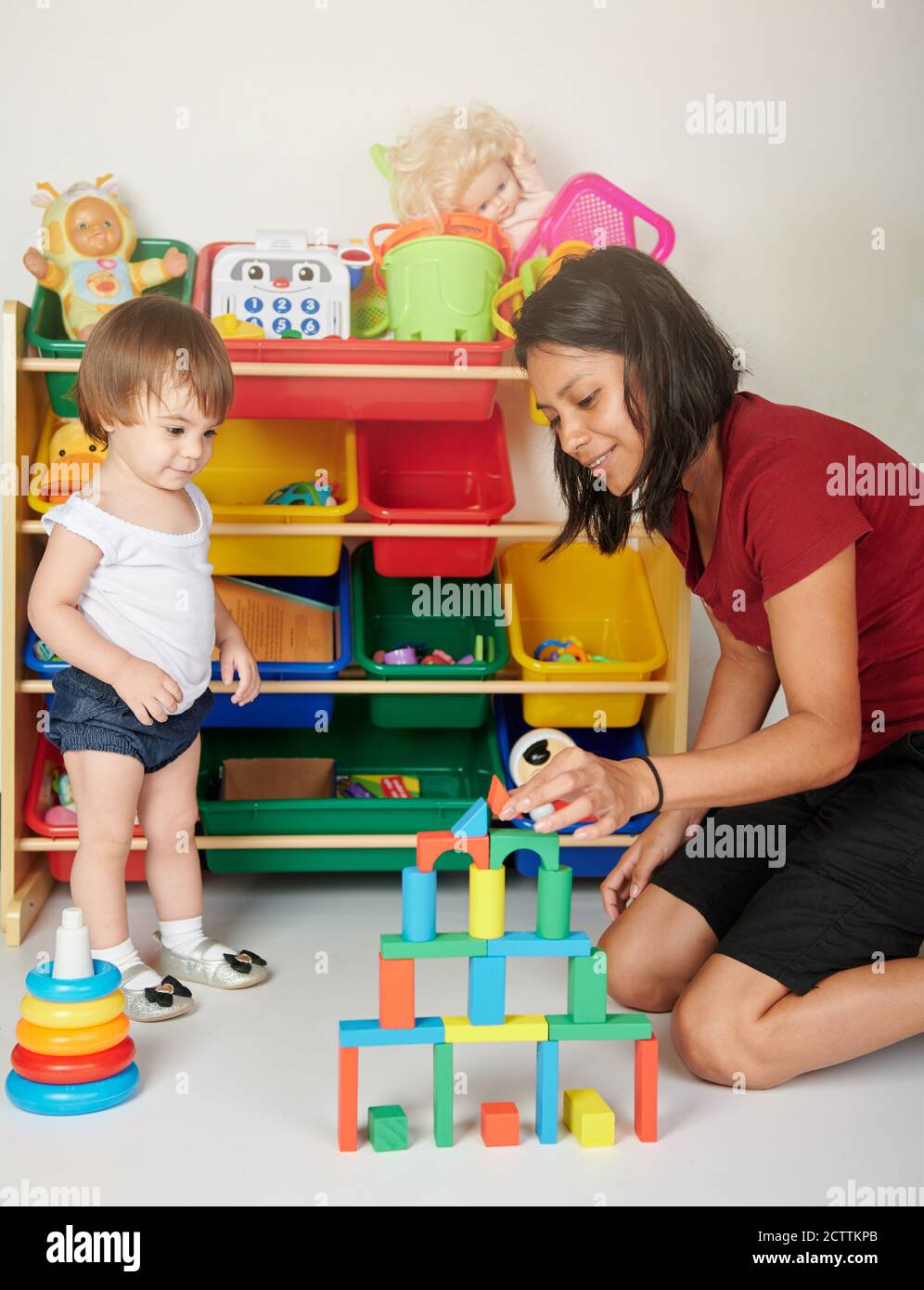 Activity for kid in daycare. Young girl play with baby wooden bricks Stock Photo