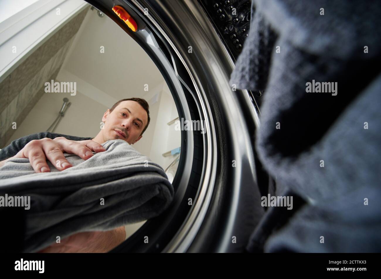 Young man using washing machine view from inside Stock Photo
