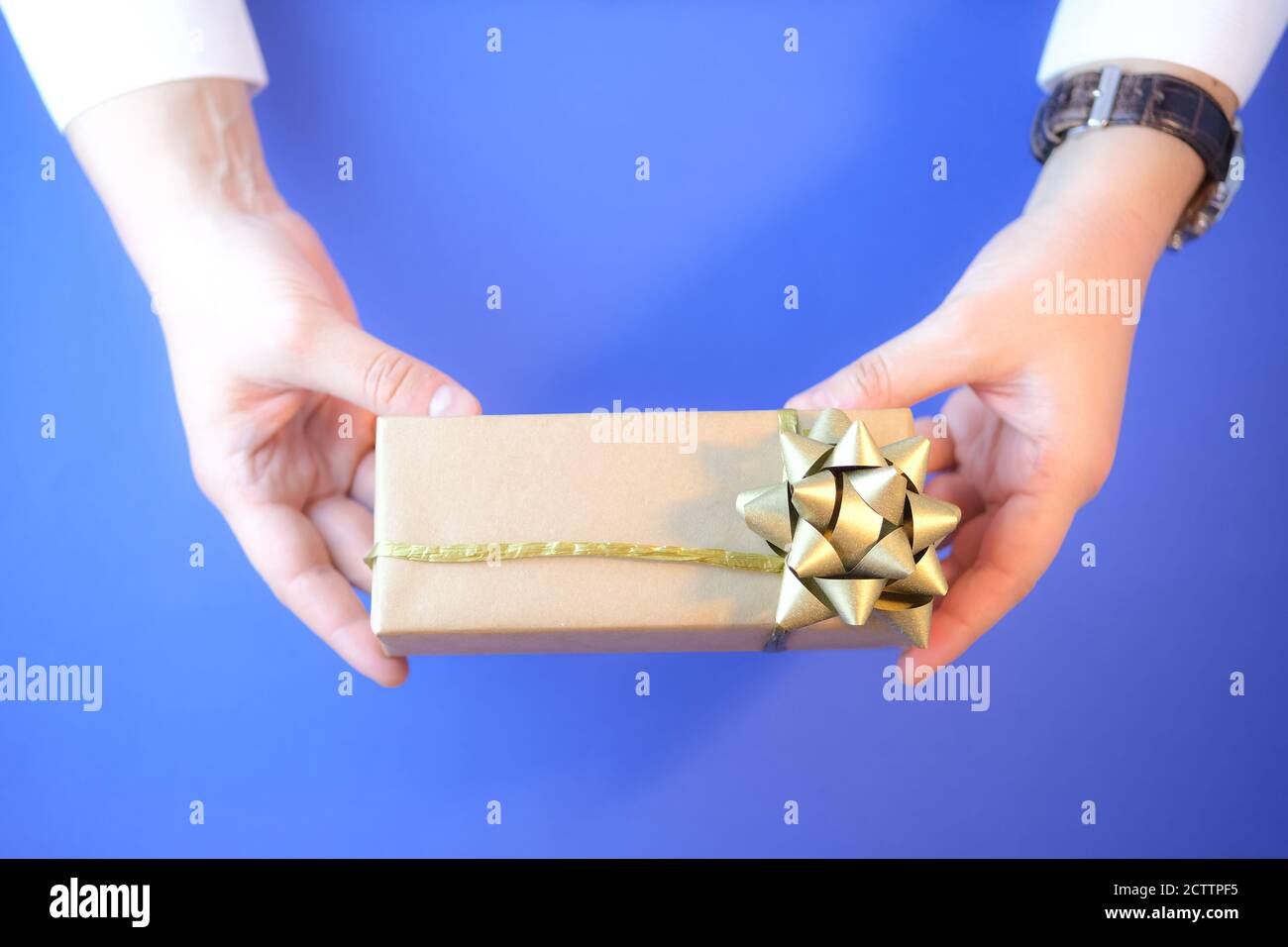 Cropped image of a man holding a gift box wrapped in craft paper. Stock Photo