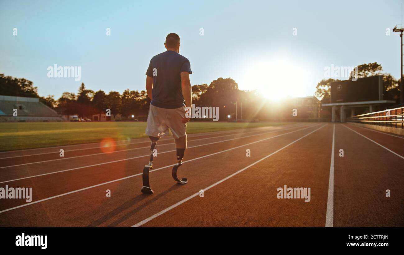 Athletic Disabled Fit Man with Prosthetic Running Blades is Walking During a Training on an Outdoor Stadium on a Sunny Afternoon. Amputee Runner Stock Photo