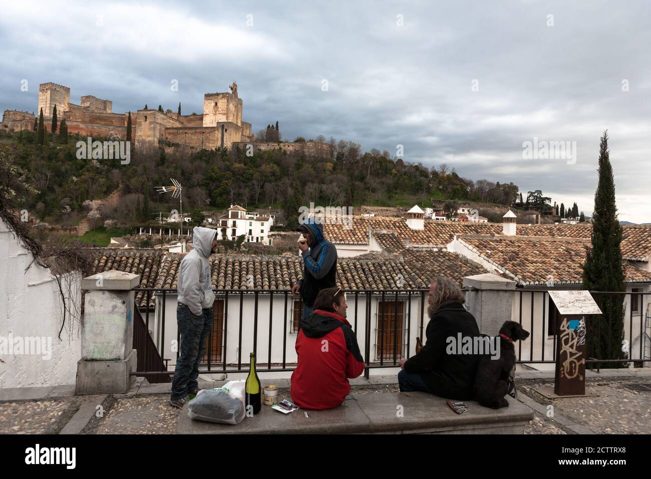 A group of itinerant vagabonds in Placeta Carvajales,  El Albaicín, Granada, Andlusia, Spain, with the Alhambra on the opposite side of the valley Stock Photo